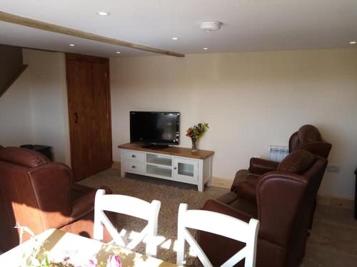 a living room with two chairs and a television at Rural getaway with a view - Old Spout Barn in Sedbergh