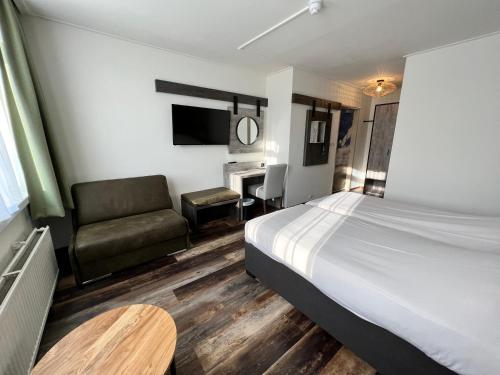 a hotel room with a bed and a couch and a table at Hotel Nap in West-Terschelling