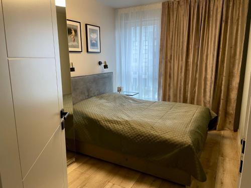 um pequeno quarto com uma cama e uma janela em Uroczy Apartament 38 m2 Tychy, Śląskie Ogrody em Tychy