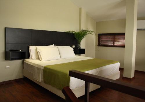 een slaapkamer met een groot bed met een zwart hoofdeinde bij ApartTerrazas Guayaquil -Suites&Lofts- in Guayaquil