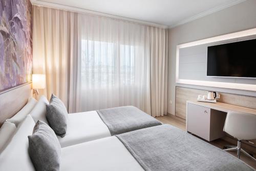 a hotel room with two beds and a flat screen tv at Salles Ciutat del Prat Barcelona Airport in El Prat de Llobregat