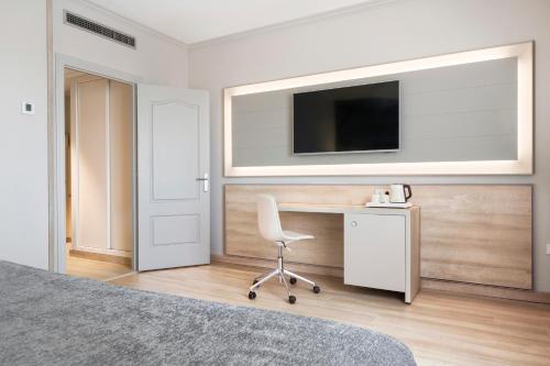 a bedroom with a desk and a chair and a tv at Salles Ciutat del Prat Barcelona Airport in El Prat de Llobregat