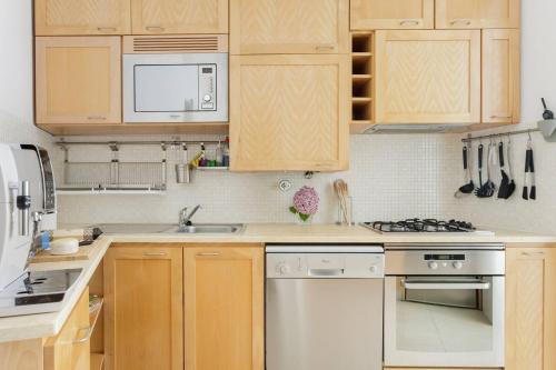 a kitchen with wooden cabinets and white appliances at Santos River View Terrace Duplex in Lisbon