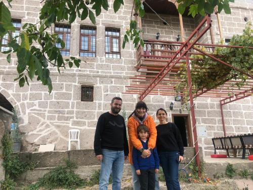 a family standing in front of a stone building at Kapadokya Ihlara Günalp Konağı in Guzelyurt