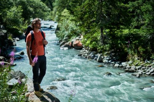 a woman walking across a river with a backpack at Le Massif Hotel & Lodge Courmayeur The Leading Hotels of the World in Courmayeur