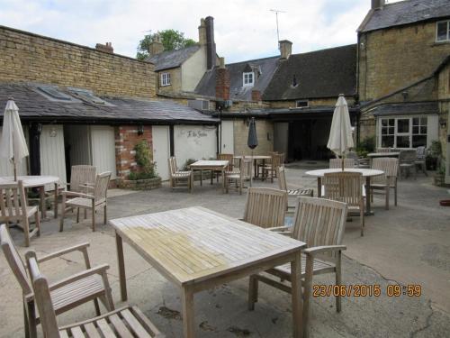 an outdoor patio with tables and chairs and umbrellas at The Bell Inn in Moreton in Marsh