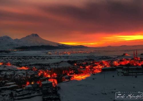 a sunset over a city with a mountain in the background at Kapadokya Ihlara Günalp Konağı in Guzelyurt