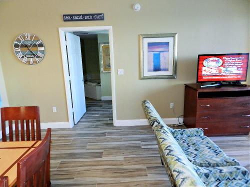 a living room with a couch and a tv at 3 BR Direct Oceanfront Condo Wyndham Ocean Walk Resort - Daytona Funland 1023 in Daytona Beach