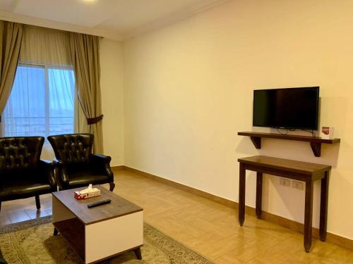 uma sala de estar com 2 cadeiras e uma televisão de ecrã plano em Ream Hotel Amman em Amã