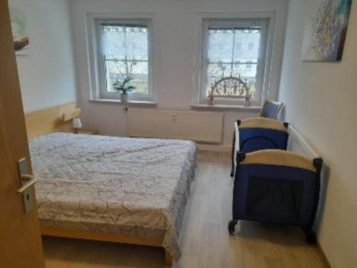 1 Schlafzimmer mit einem Bett, 2 Stühlen und 2 Fenstern in der Unterkunft Ferienwohnung Zern in Johanngeorgenstadt