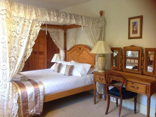 a bedroom with a canopy bed and a desk at St Peters Bed and Breakfast in Sandwich
