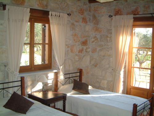a bedroom with two beds and a stone wall at Villa Karissa - Zante in Vasilikos