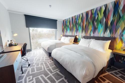 a hotel room with two beds and a colorful wall at Village Hotel Bracknell in Bracknell