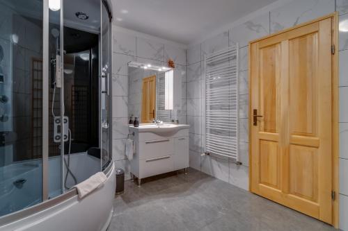 La salle de bains est pourvue d'une douche, d'un lavabo et d'une baignoire. dans l'établissement Apartman "Ela", à Fužine