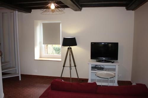 ein Wohnzimmer mit einem Sofa und einem TV in der Unterkunft Ty Daou - Gîtes du Vieux Tilleul in Tréglamus