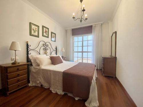 een slaapkamer met een bed, een dressoir en een raam bij Piso Os Pazos in Cambados
