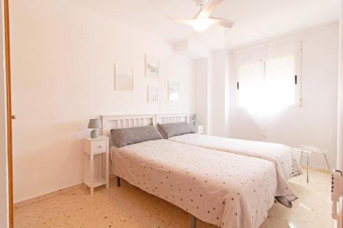 ein weißes Schlafzimmer mit 2 Betten und einem Fenster in der Unterkunft Global Properties, Increible apartamento en la playa, Canet d'en Berenguer in Canet d'en Berenguer