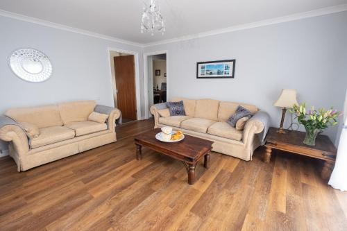 a living room with two couches and a coffee table at Mill House Bungalow in Potter Heigham