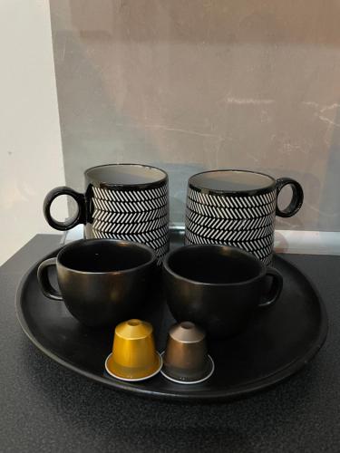 three black cups on a black plate on a table at PALAZZO FIACCADORI - Historical Palace in Reggio di Calabria