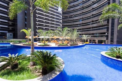 una gran piscina con palmeras frente a un edificio en Apartamento Beira Mar by WL Temporada, en Fortaleza