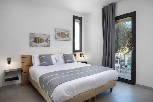 a white bedroom with a large bed and a window at The Square Cannigione in Cannigione
