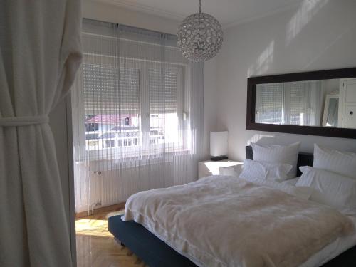 a bedroom with a large white bed and a chandelier at Kuća za odmor Dugo Selo M&A in Dugo Selo