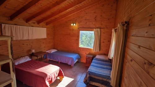 Habitación con 2 camas y ventana en una cabaña de madera. en Lo De Pablo en Villa La Angostura