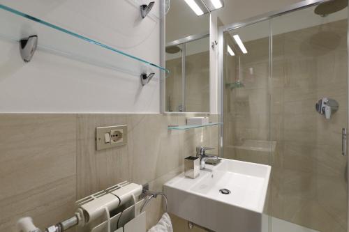 łazienka z umywalką i przeszkloną kabiną prysznicową w obiekcie Contempora Apartments - Elvezia 8 - E51 w Mediolanie
