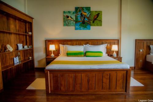 a bedroom with a large wooden bed with two green pillows at Lagoon gate Tangalle Resort in Tangalle