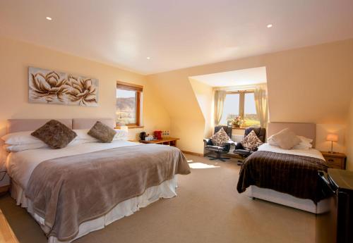 a bedroom with two beds and a chair in it at Tigh an Each B&B & Laggan Glamping in Newtonmore