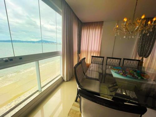 uma sala de jantar com uma mesa e vista para o oceano em Cobertura Infinity Blue - Itapema/SC em Itapema