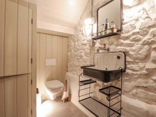 a bathroom with a sink and a stone wall at Dolwylan Barn in Llandysul