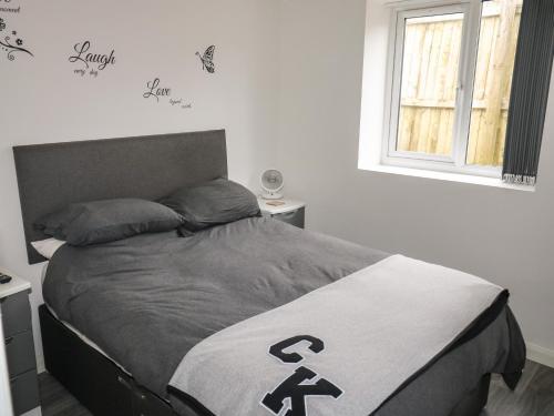 uma cama num quarto branco com uma janela em Sunnydene em Paignton