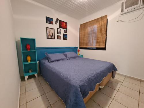 um quarto com uma cama azul e uma janela em Flat 31 SUN HOUSE Maresias em Maresias