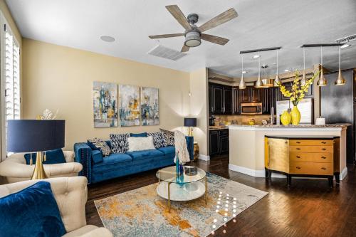 a living room with a blue couch and a kitchen at Luxury & Highly furnished upscale w Patio & Garage in Plano