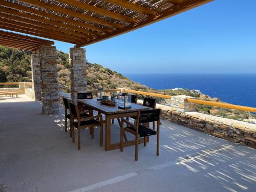 een houten tafel en stoelen op een patio met uitzicht op de oceaan bij Blue Calm Luxury Villa in Sifnos in Artemonas