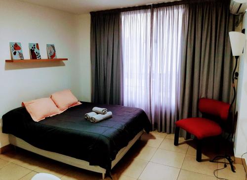 1 dormitorio con 1 cama y 1 silla roja en Catamarca Río en Rosario
