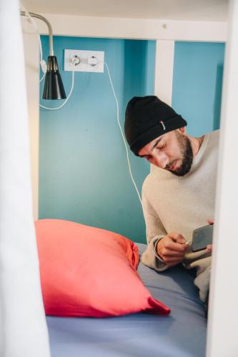 a man sitting on a bed looking at a tablet at Casa Caracol in Cádiz