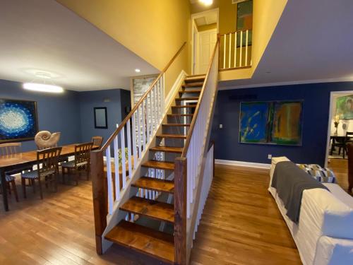 a staircase in a living room with a table and a dining room at Here It Is! Cool Cape Cod-3 BR-2.5 Bath-12 Guests in Olathe