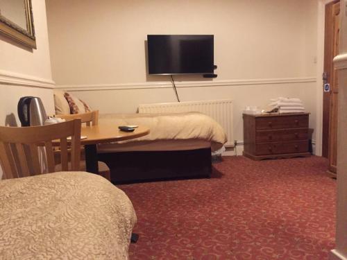 
a bedroom with a bed and a television at The Pines Guest House in Whitley Bay
