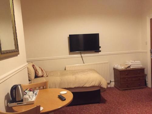 
a living room with a tv and a bed at The Pines Guest House in Whitley Bay

