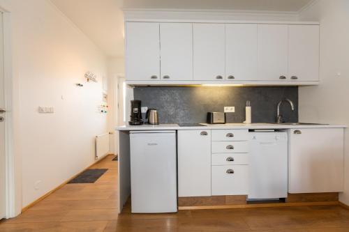 una cucina con armadi bianchi in una camera di Central Apartment with Two bedrooms and Balcony- Strandgata 9 ad Akureyri