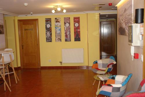 Zimmer mit gelber Wand mit Stühlen und Plakaten in der Unterkunft Hostal Campus in Burgos