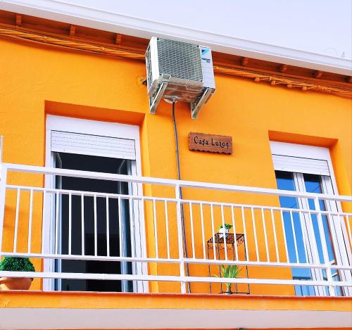 a yellow house with a balcony with a fan at Casa Luzon, terraza-solarium con ducha y salon rustico in Villarejo de Salvanés