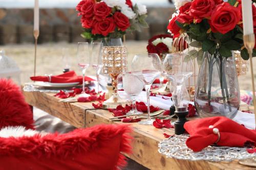 a table with red flowers and wine glasses on it at Divine Resort & Spa in Kampala