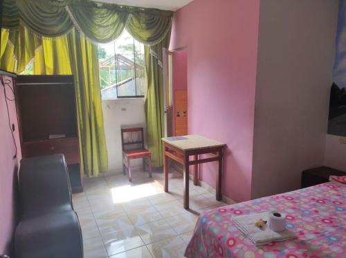 a bedroom with a bed and a table and a chair at HOSPEDAJE EL CANTARO in Tingo María