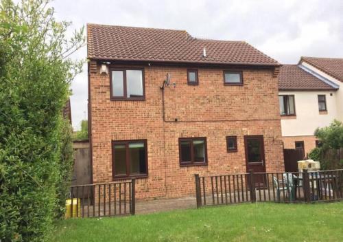 a brick house with a fence in a yard at 6 Bedroom House For Corporate Stays in Corby Suitable for Nightshift Workers in Great Oakley