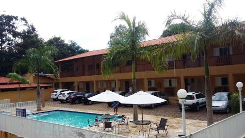 a hotel with a pool and chairs and palm trees at POUSADA RECANTO DO TRABALHADOR in Rancharia