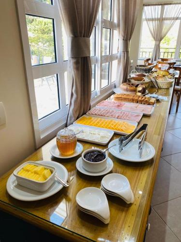a table filled with food and plates of food at Village de Charme - 2km do Capivari in Campos do Jordão