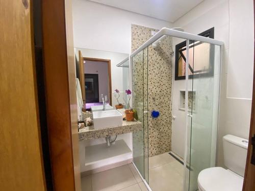 un bagno con doccia in vetro e lavandino di Suíte aconchegante a Ilhabela